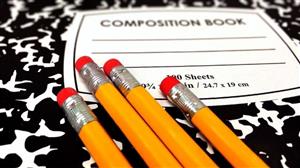 Four yellow pencils on top of a black and white composition book 